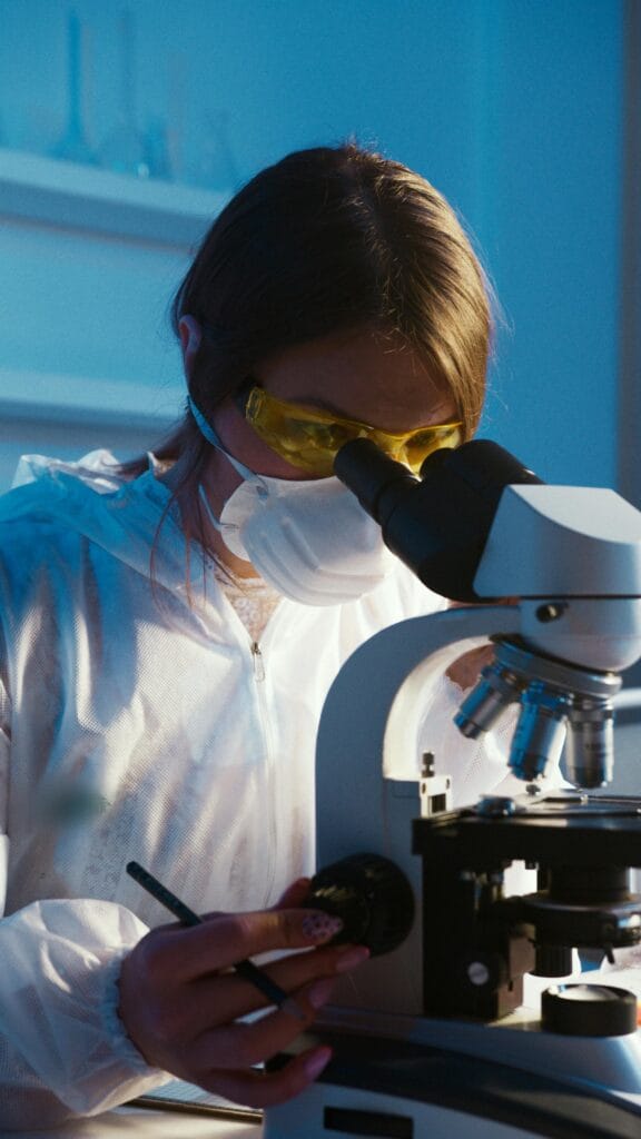 About Us A female scientist examines a sample using a microscope in a laboratory setting.